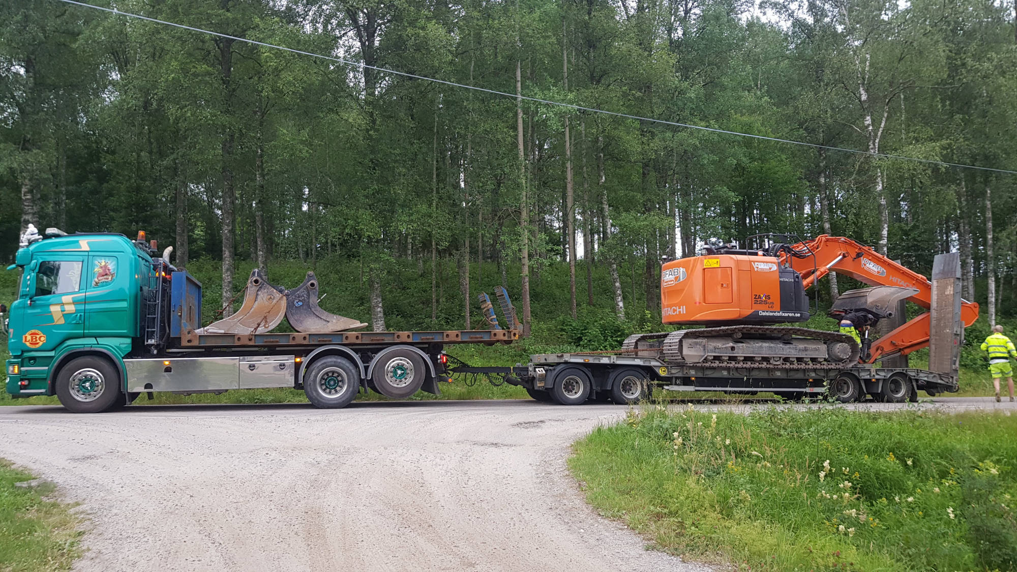 En trailer kommer lastad med Grävmaskin